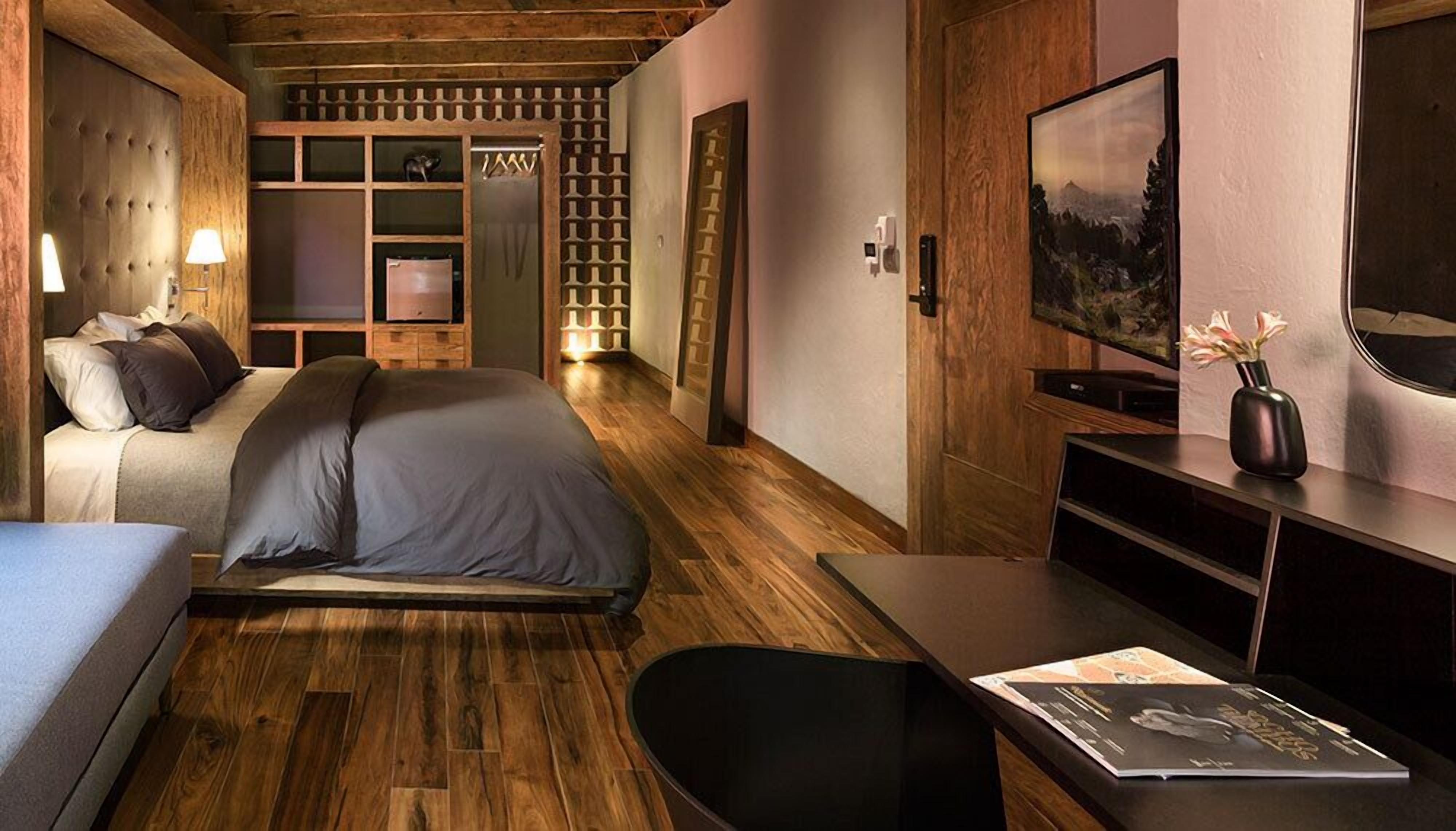 Un dormitorio moderno con una cama grande, un escritorio, una silla, un televisor y una estantería.
