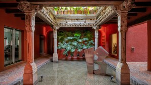 An ornate courtyard with a central planter, stone columns, and a tiled floor. - Morada La Noria (Puebla)