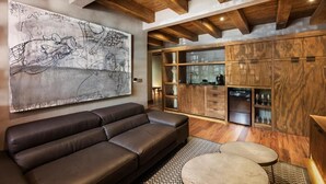 A modern living room with a large abstract painting, a leather sofa, a coffee table, and wooden cabinetry with glass doors. - Morada La Noria (Puebla)