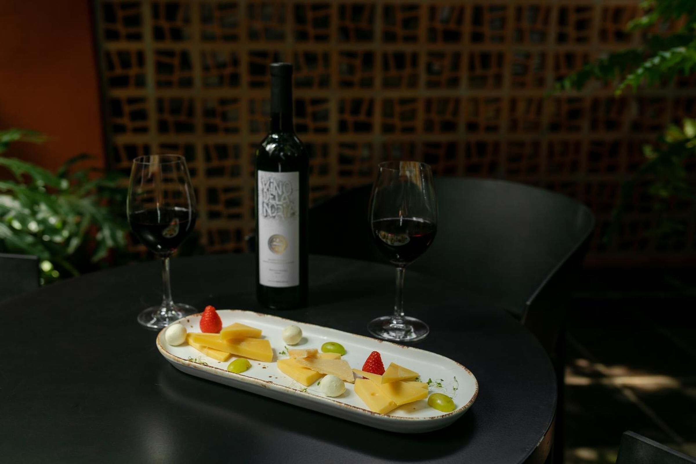 Ein Tisch mit Käse, Trauben, zwei Weingläsern und einer Weinflasche.
