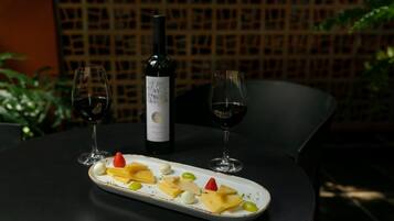 Ein Tisch mit Käse, Trauben, zwei Weingläsern und einer Weinflasche.