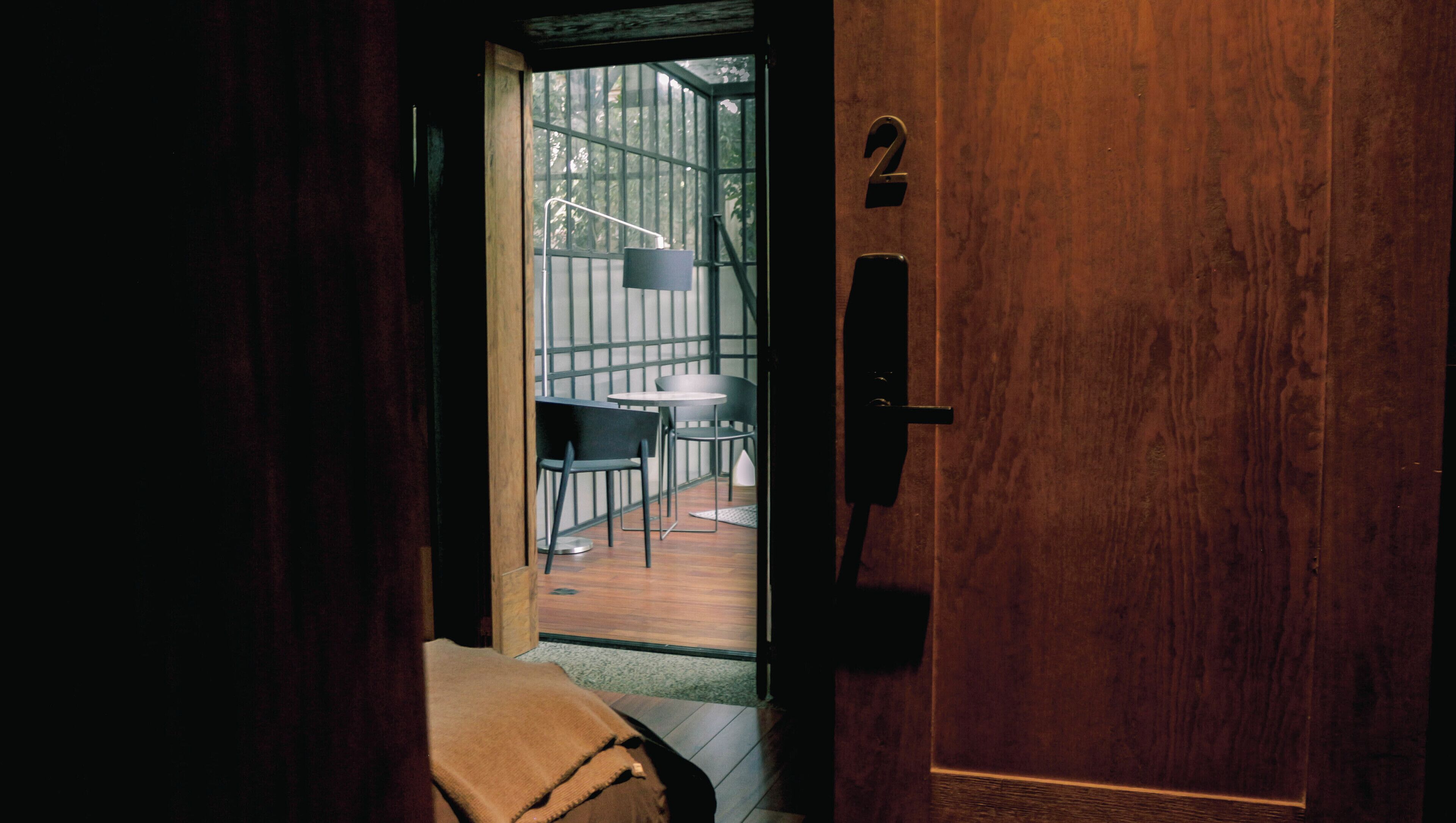 A wooden door with a number '2' sign, leading to an outdoor area with a table and chairs.