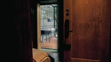 A wooden door with a number '2' sign, leading to an outdoor area with a table and chairs.