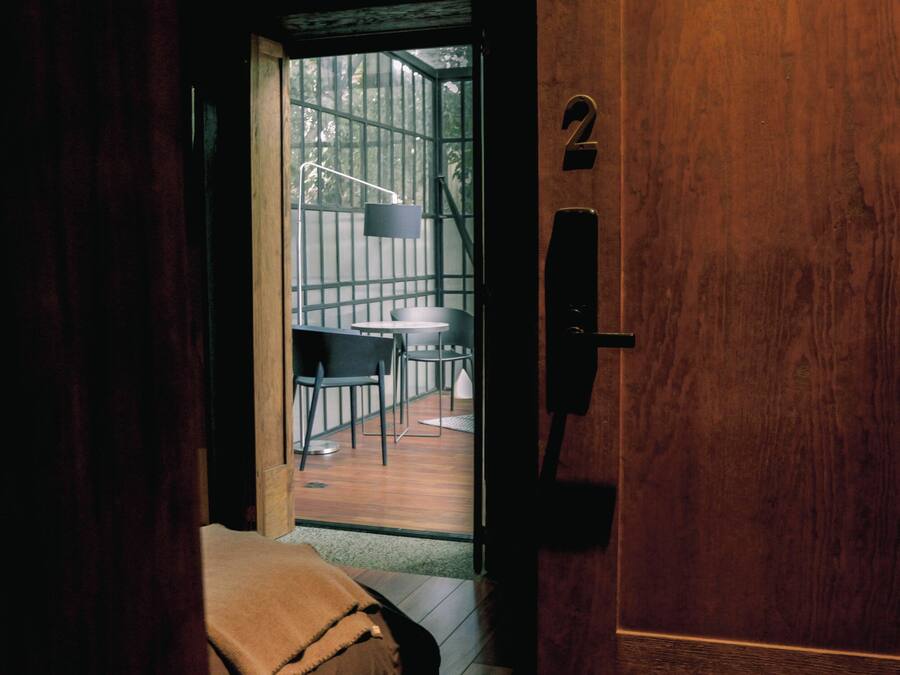 A wooden door with a number '2' sign, leading to an outdoor area with a table and chairs.