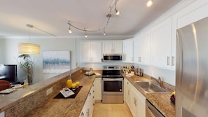 Enjoy cooking in this well-equipped kitchen with a double sink, microwave, stove, and refrigerator.