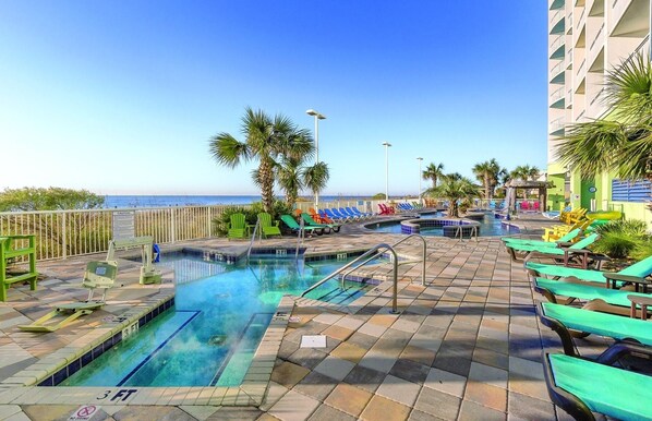 Relax by the oceanfront pool surrounded by lounge chairs and palm trees.