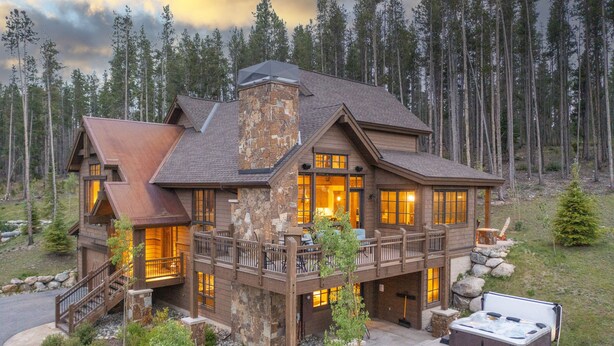 Un grand chalet à plusieurs étages, doté d’une cheminée en pierre, de balcons en bois et d’un jacuzzi situé dans le jardin.