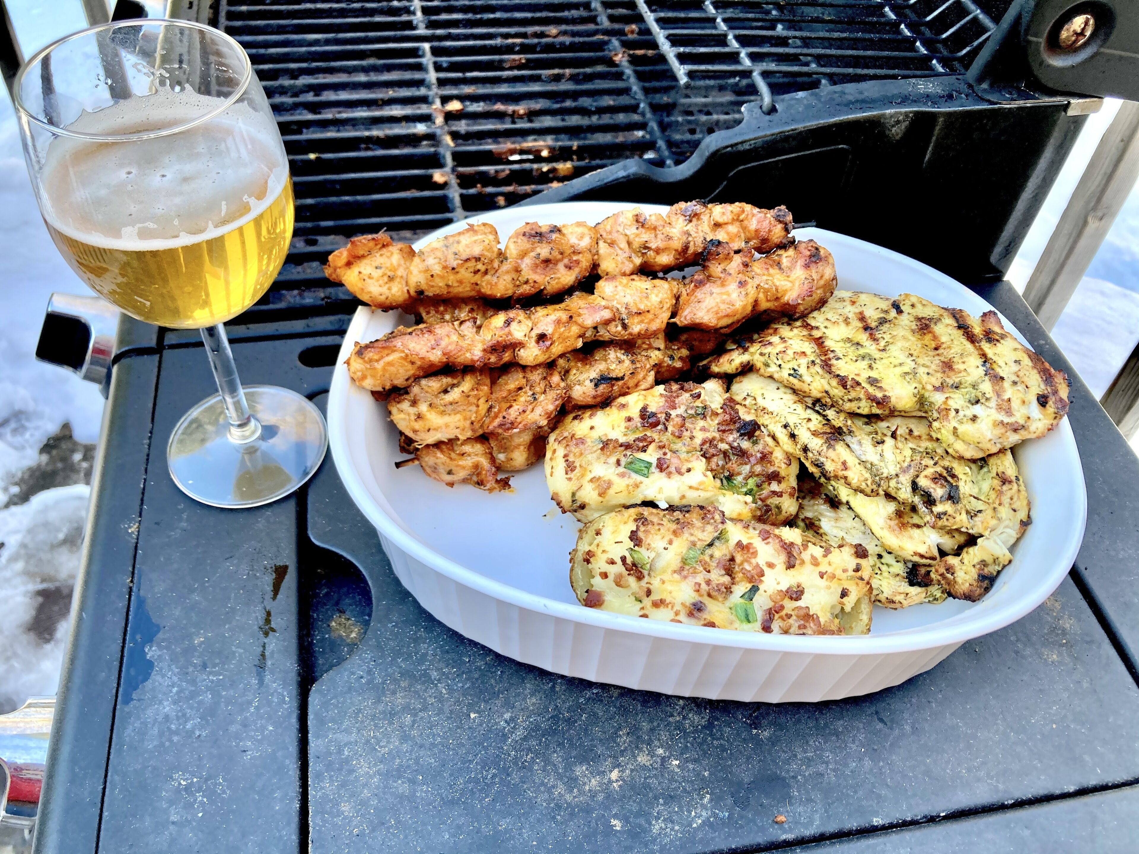 Een barbecue met eten en een glas bier op een tafel.