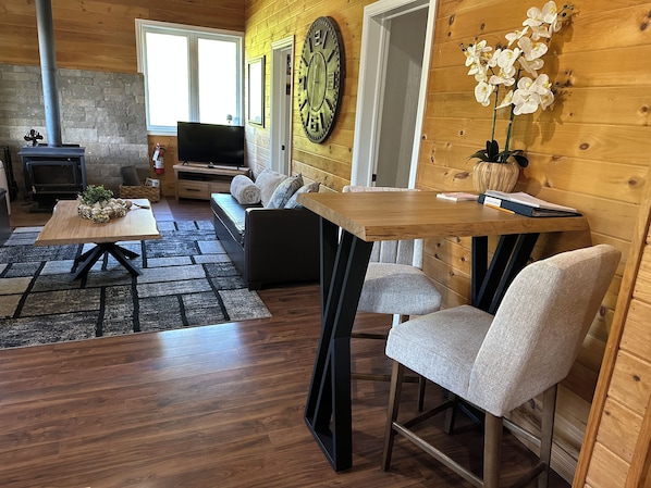 A cozy living room with a fireplace, sofa, and a dining area with chairs and a table.