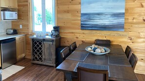Een houten chalet van binnen met een keuken, eethoek en een groot raam.