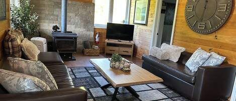 Un salon chaleureux avec une cheminée, un téléviseur et des fauteuils confortables.