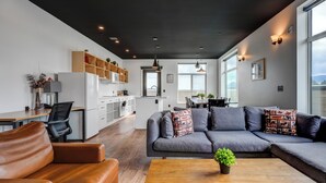 A modern living room with a sofa, coffee table, and a dining area with a table and chairs. - Raven Inn Whitehorse (Whitehorse)