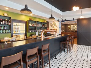 A bar area with a counter, stools, and shelves of bottles. - Raven Inn Whitehorse (Whitehorse)