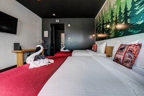 Ein Hotelzimmer mit zwei Betten, einem Flachbildfernseher, einem Schreibtisch und einem Wandbild mit Bäumen.
