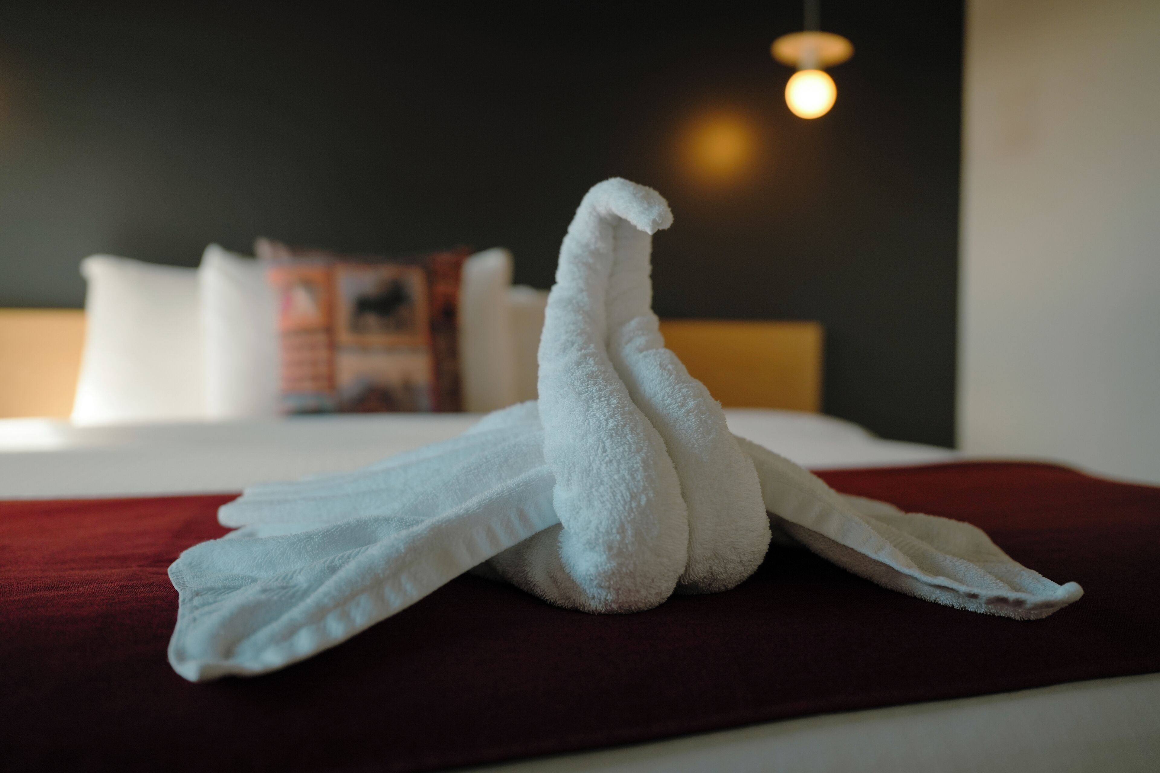 A neatly folded towel on a bed with a red blanket.