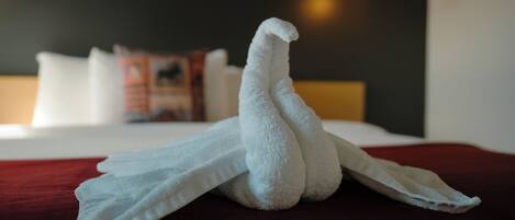 A neatly folded towel on a bed with a red blanket.