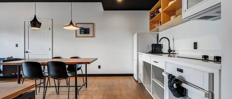 Una cocina moderna con armarios blancos, una mesa de comedor de madera y sillas negras.