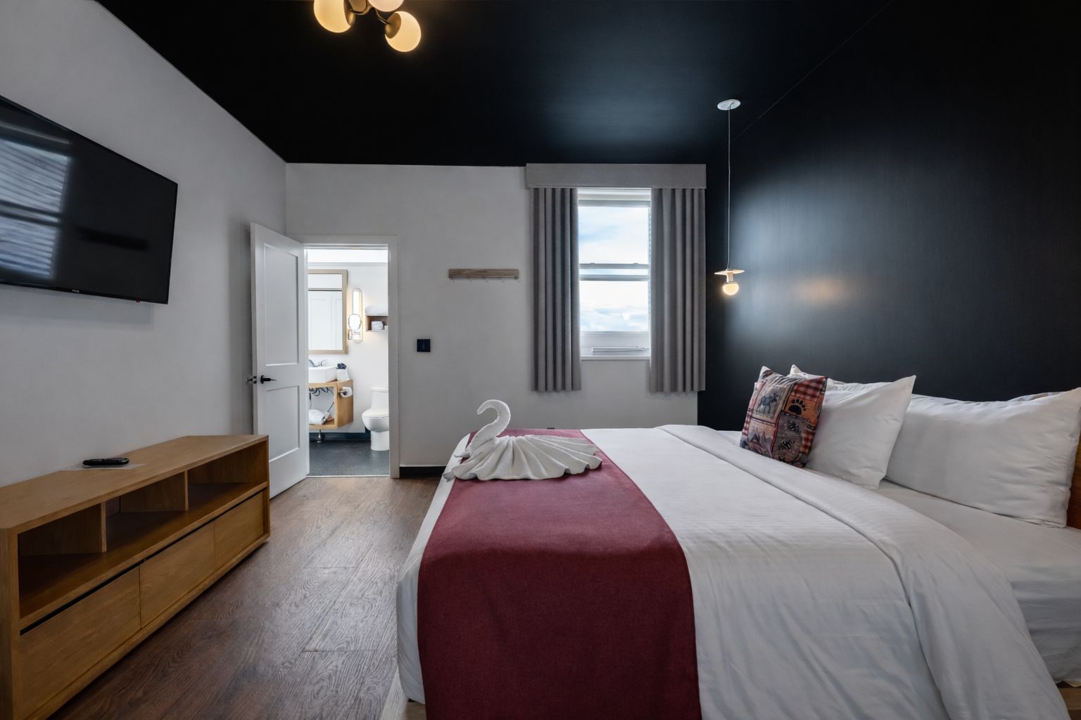 Een moderne hotelkamer met een groot bed, een houten console en een flatscreen televisie, met uitzicht op de stad.