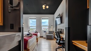 A modern hotel room with a bed, desk, chair, and large windows. - Raven Inn Whitehorse (Whitehorse)