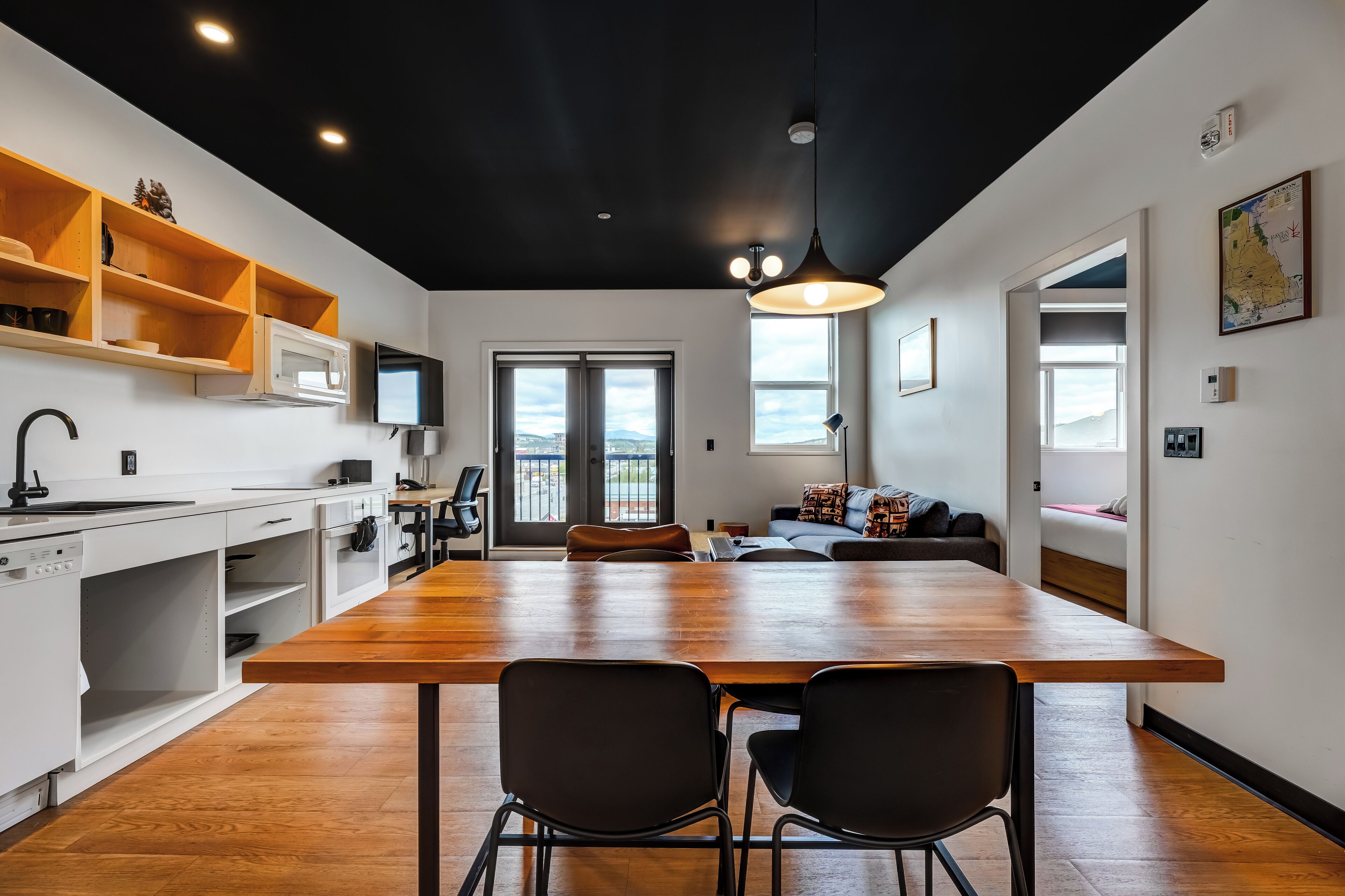 Una cocina moderna con una isla de madera, armarios blancos y una zona de comedor con dos sillas.