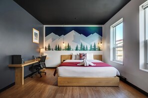 Ein Schlafzimmer mit Bett, Schreibtisch und einem Gemälde von Bergen und Bäumen.