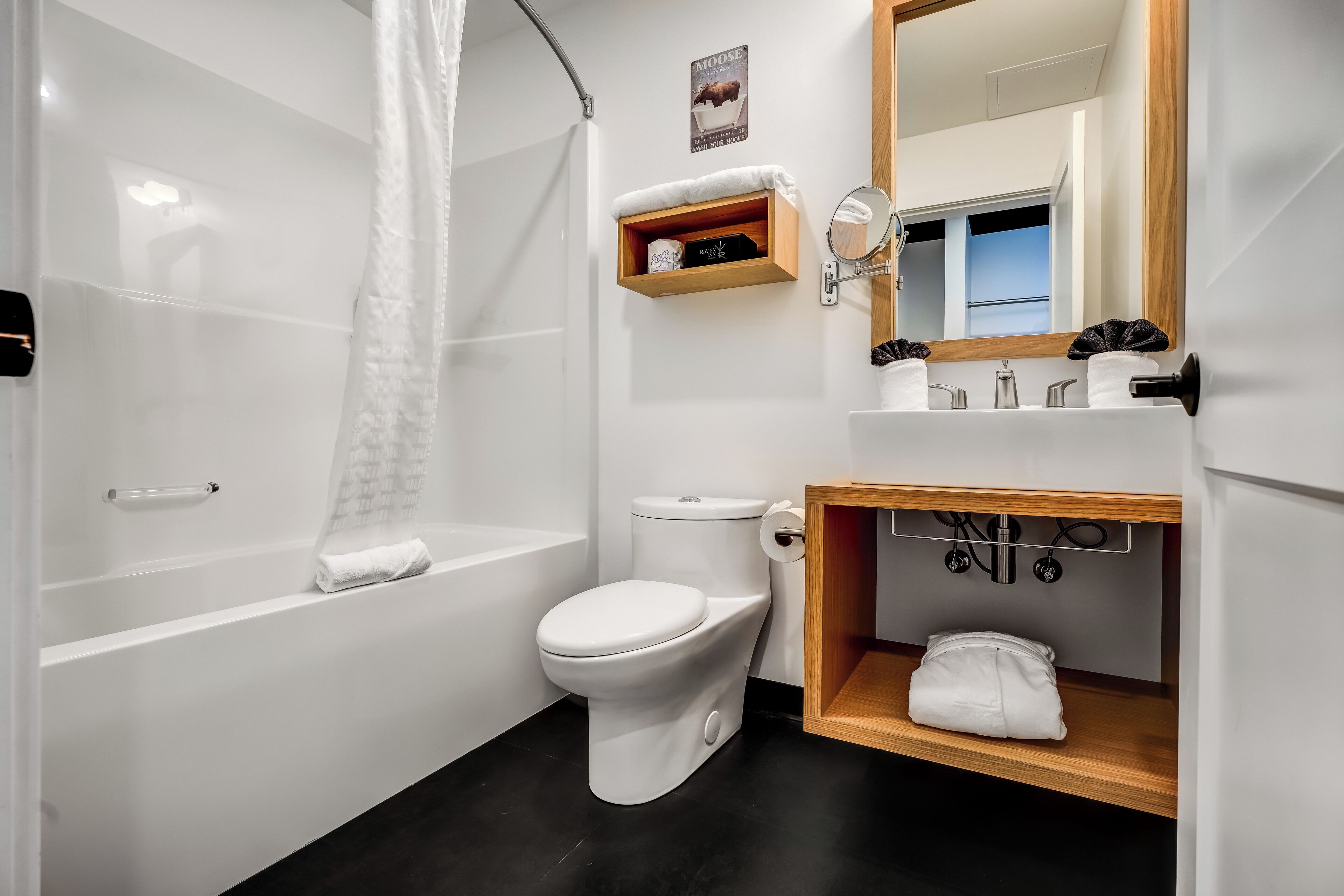 A modern bathroom with a bathtub, toilet, and vanity.