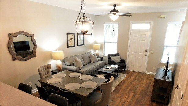 A dining area with a wooden table and chairs, a sofa, and a ceiling fan.