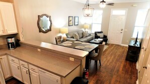 A modern kitchen with a dishwasher, a coffee maker, and a dining area with a table and chairs.