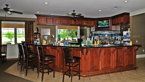A spacious kitchen with a large island, wooden cabinets, and a bar area with stools.