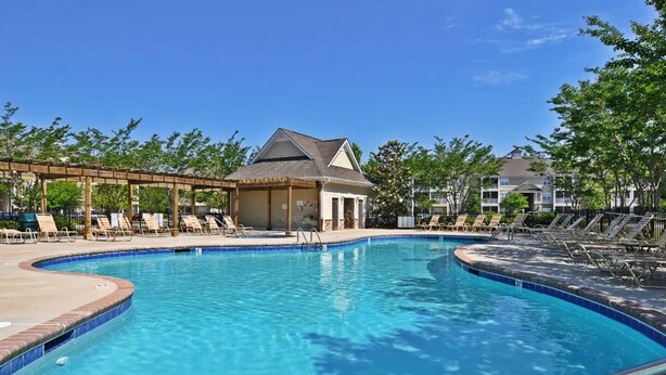A swimming pool with lounge chairs and a covered pavilion.