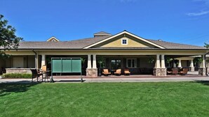 A two-story building with a covered patio area, outdoor seating, and a well-maintained lawn.