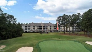 Un campo de golf con un club de campo al fondo.