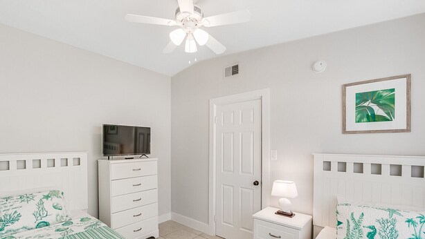 A bedroom with two beds, a TV on a dresser, a door, and a ceiling fan. - RIVERFRONT community in COCOA BEACH with short walk to the beach!! (Cocoa Beach)