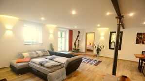Ein modernes Wohnzimmer mit Ecksofa, Holzböden und Wandleuchten.