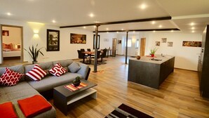 Ein modernes Wohnzimmer mit Sofa, Couchtisch und einem Essbereich mit Stühlen und Tisch.
