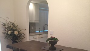 Una cucina con un'isola in legno scuro, due sgabelli e un vaso con fiori.