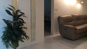 Un soggiorno moderno con un divano beige, una pianta in vaso e lampade a sospensione.