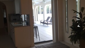 Un'ampia zona giorno con cucina, una sala da pranzo con sedie e vista sul patio esterno.