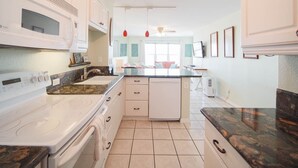 A modern kitchen with white cabinetry, a central island, a built-in oven, and a dishwasher. - Relaxing , Great Location, 3 Minute Walk To The Beach 2 Bedroom Condo by RedAwning (South Padre Island)