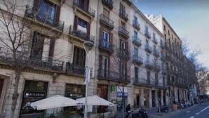 A row of multi-story buildings with balconies, outdoor seating with umbrellas, and parked motorcycles. - Pau Claris | Design 1BR home near Paseo de Gracia (Barcelona)