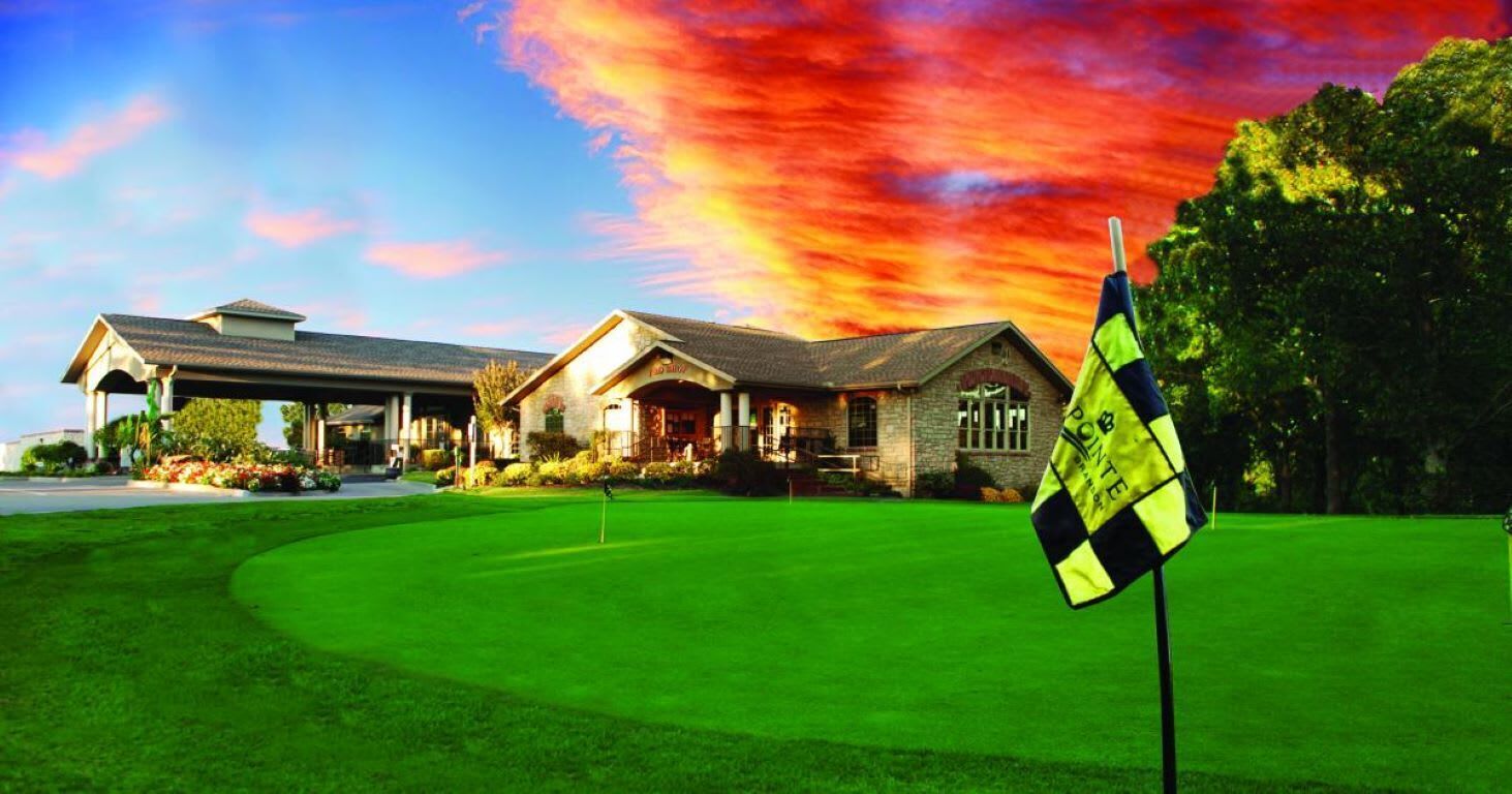 Un parcours de golf doté d’un club-house et d’un drapeau sur un mât.