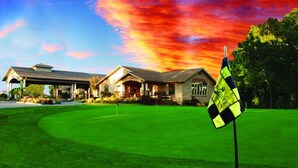 En golfbana med ett klubbhus och en flagga på en flaggstång.