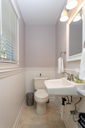 A bathroom with a toilet, sink, and window with blinds.