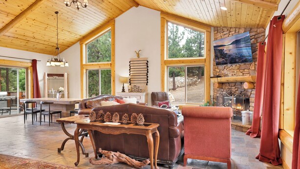 A spacious living room with a stone fireplace, large windows, and a cozy seating area. - Eagle Ridge Views #1648 (Big Bear Lake)