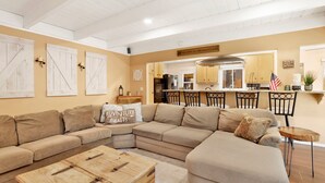 A cozy living room with a sectional sofa, a wooden coffee table, and a kitchen area with wooden cabinets and a bar. - Cozy UP TO Summit #1651 (Big Bear Lake)