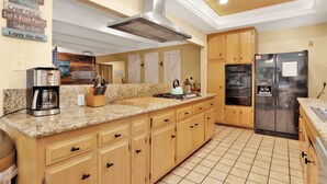 A kitchen with wooden cabinets, a stainless steel range hood, a coffee maker, and a refrigerator. - Cozy UP TO Summit #1651 (Big Bear Lake)