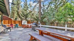 A wooden deck with picnic tables and chairs, a barbecue grill, and a wooden fence. - Cozy UP TO Summit #1651 (Big Bear Lake)