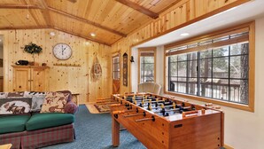 Una habitación acogedora con detalles de madera, una mesa de fútbol de mesa, un sofá y un amplio ventanal con vistas al exterior.