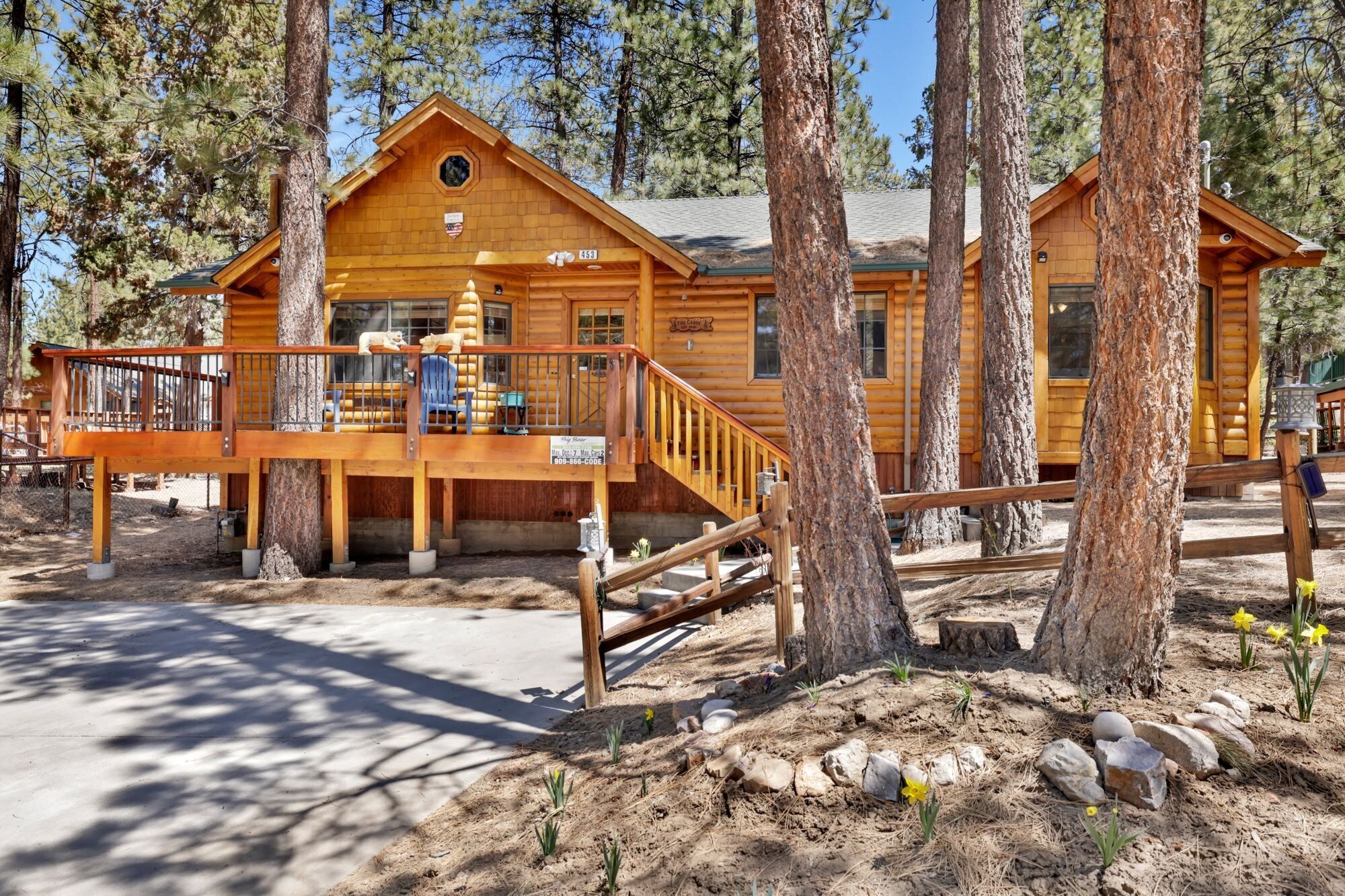 A wooden cabin with a deck, surrounded by trees.