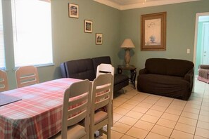 Un salon avec une table à manger dressée pour quatre personnes, un canapé et une lampe.